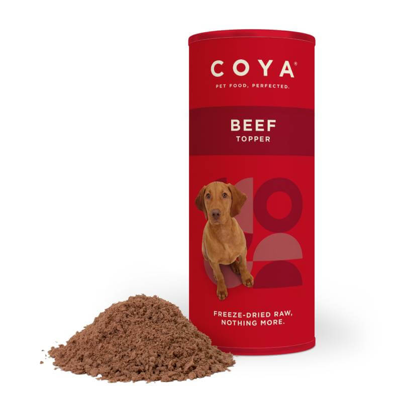Coya Adult Dog Topper Beef 50g canister next to a pile of freeze dried beef powder.
