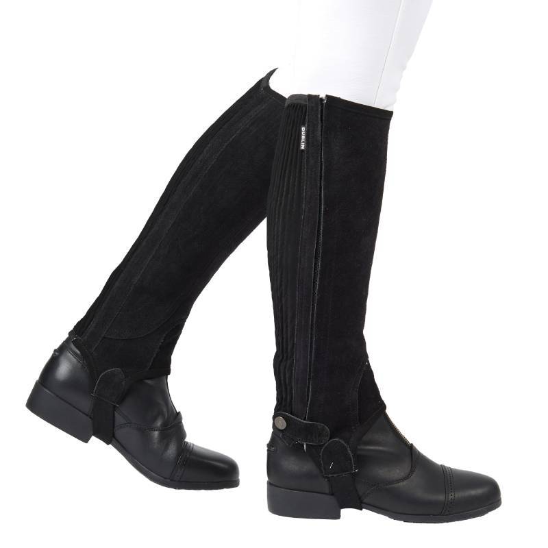 Child wearing Dublin Suede Half Chaps II Black over white pants and black riding boots, side view.