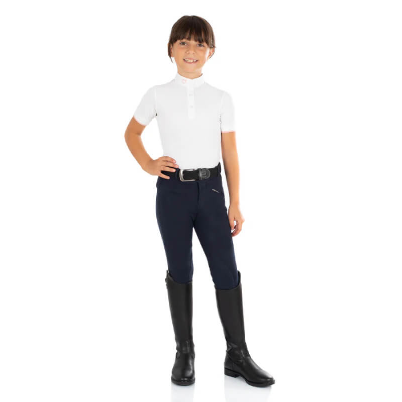 Smiling child in Equestro Kasumi Navy junior breeches, black boots, and a white shirt.