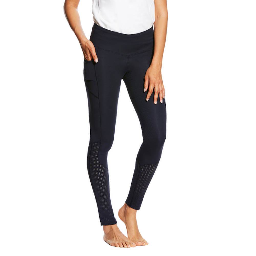 Woman in Ariat Womens Eos Full Seat Tights and white top, barefoot with hand in pocket.