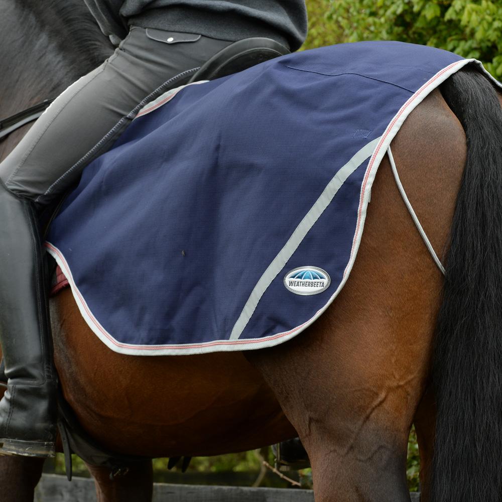 A rider uses the Weatherbeeta 600D Exercise Sheet on their horse's hindquarters.