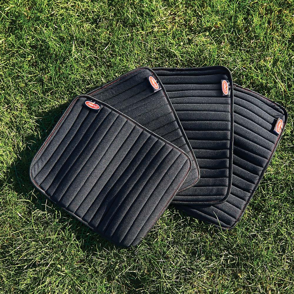 Four black/red Weatherbeeta Therapy-Tec Channel Quilt Leg Pads on green grass.