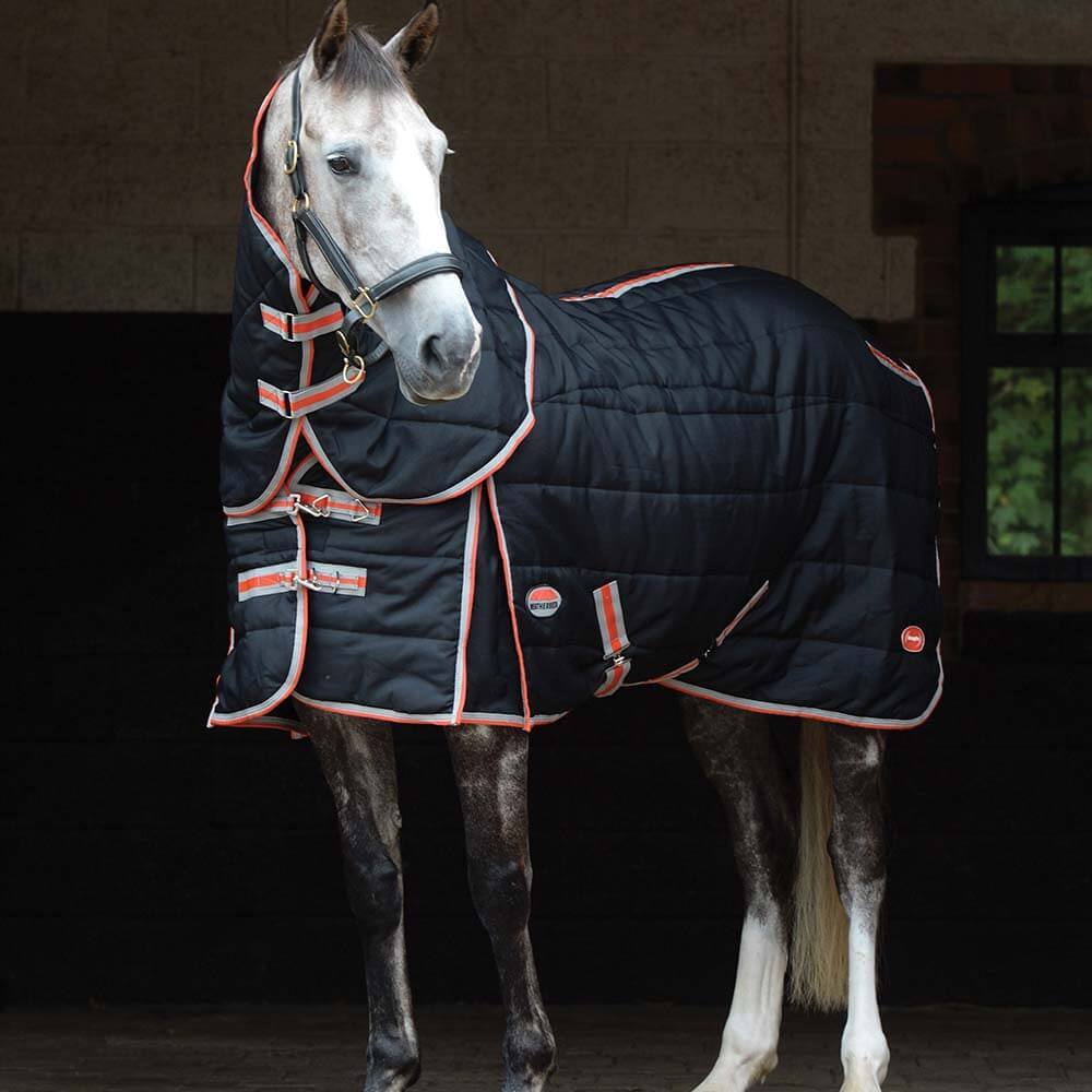 Gray horse wears Weatherbeeta Comfitec Channel Quilt Therapy Tec blanket in stable doorway.