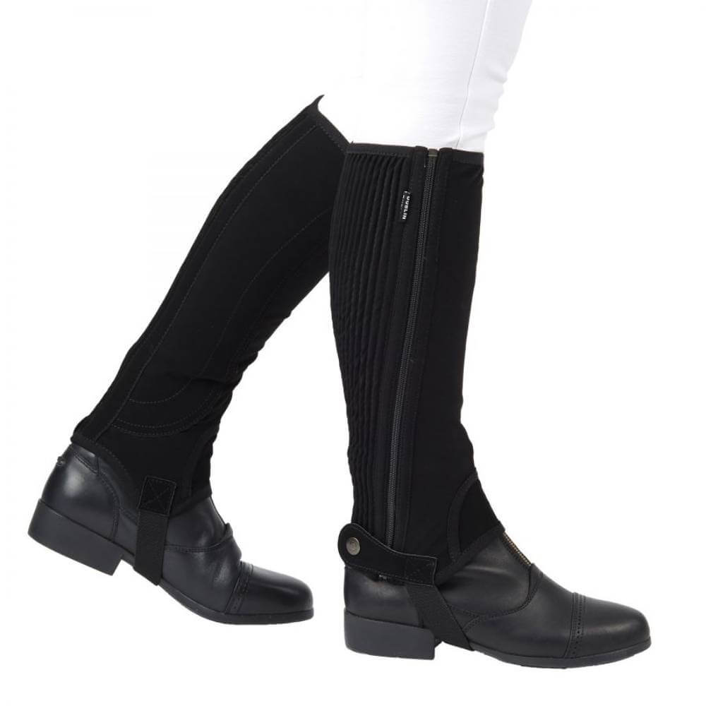 Child in white pants wears Dublin Easy Care Childs Half Chaps Black, side view.