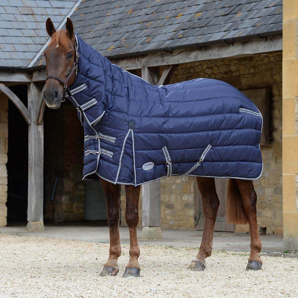 A brown horse in a Weatherbeeta Comfitec PP Channel Quilt II Combo Heavy stands in a courtyard.