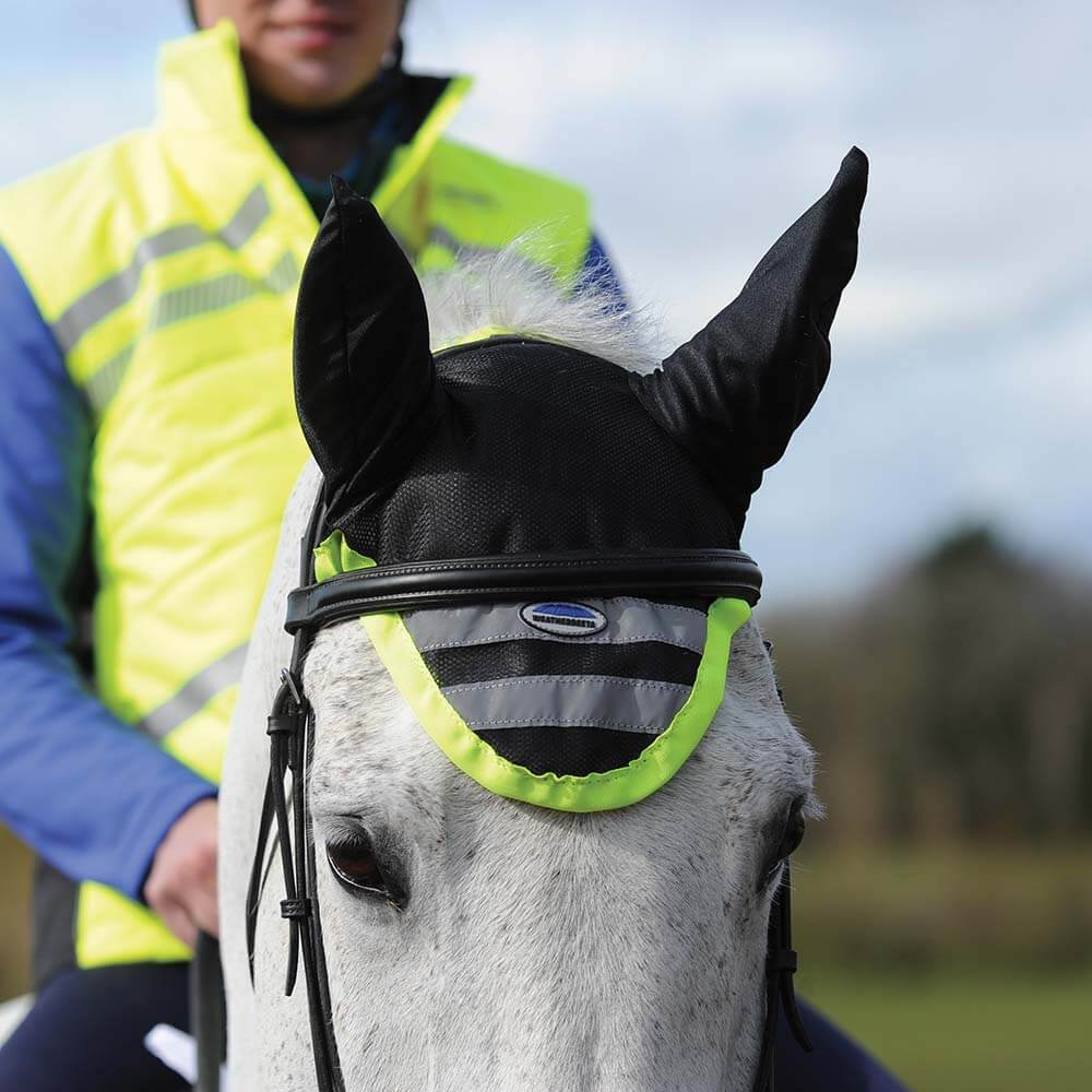 A rider in a yellow vest on a white horse with a Weatherbeeta Reflective Ear Bonnet Yellow.