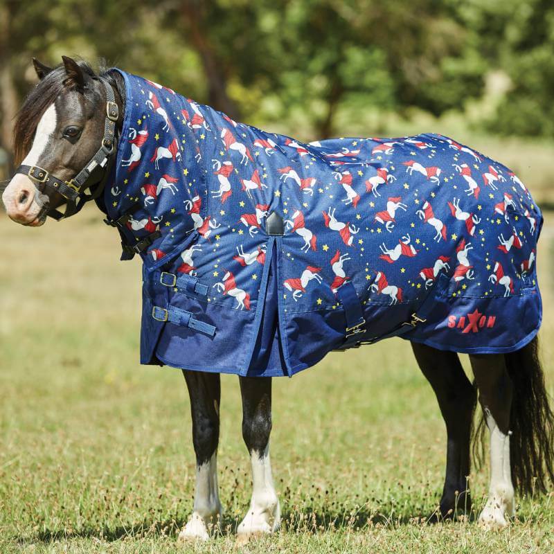 A pony wears a Saxon 600D Pony Combo Neck rug in blue unicorn print, standing outdoors.