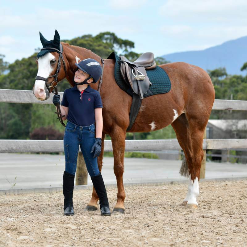 Girl in riding gear stands by a horse with a Weatherbeeta Prime Saddle Pad Reflecting Pond.