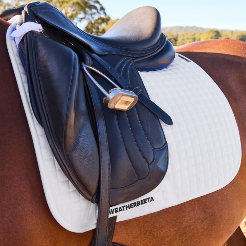 Black saddle and stirrup on a Weatherbeeta Prime Air-Tec Dressage Saddle Pad in white.