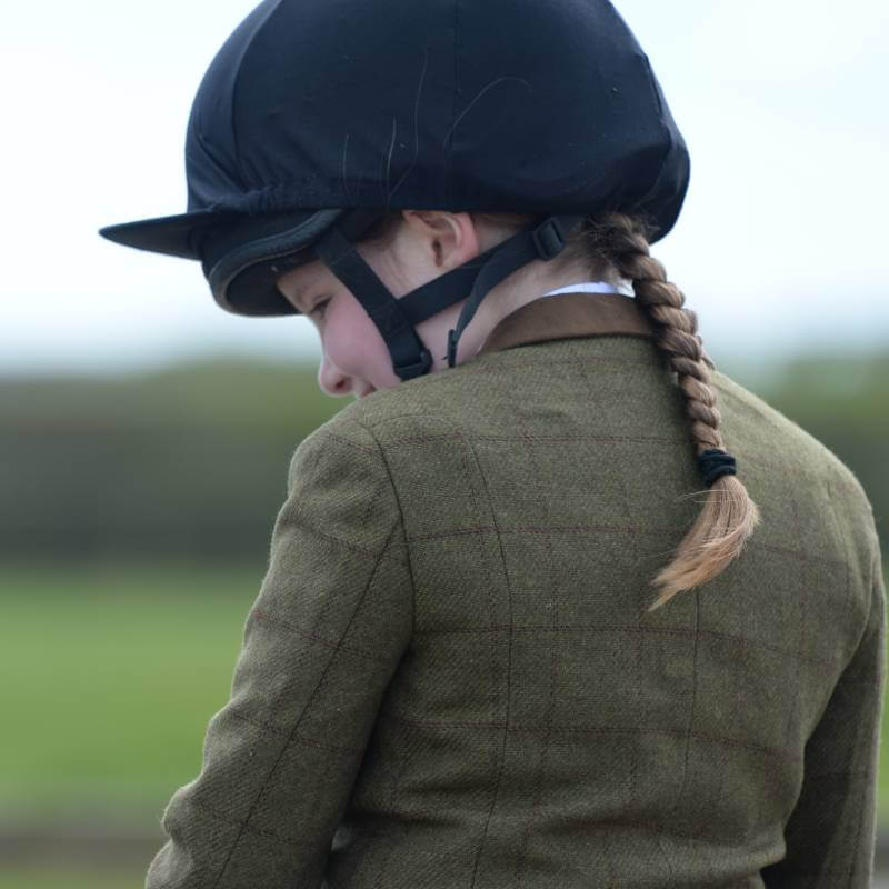 Child wearing Dublin Albany Tweed Suede Collar Jacket, helmet, braided ponytail, outdoors.
