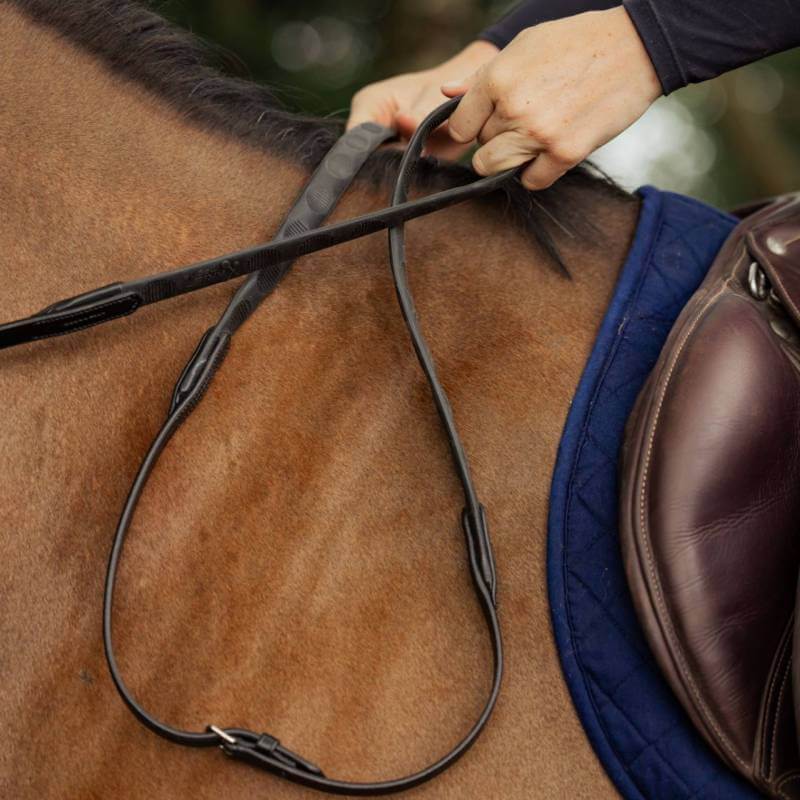 Hands adjusting Mackey Classic Precision Grip Reins Black on a brown horse with blue saddle pad.